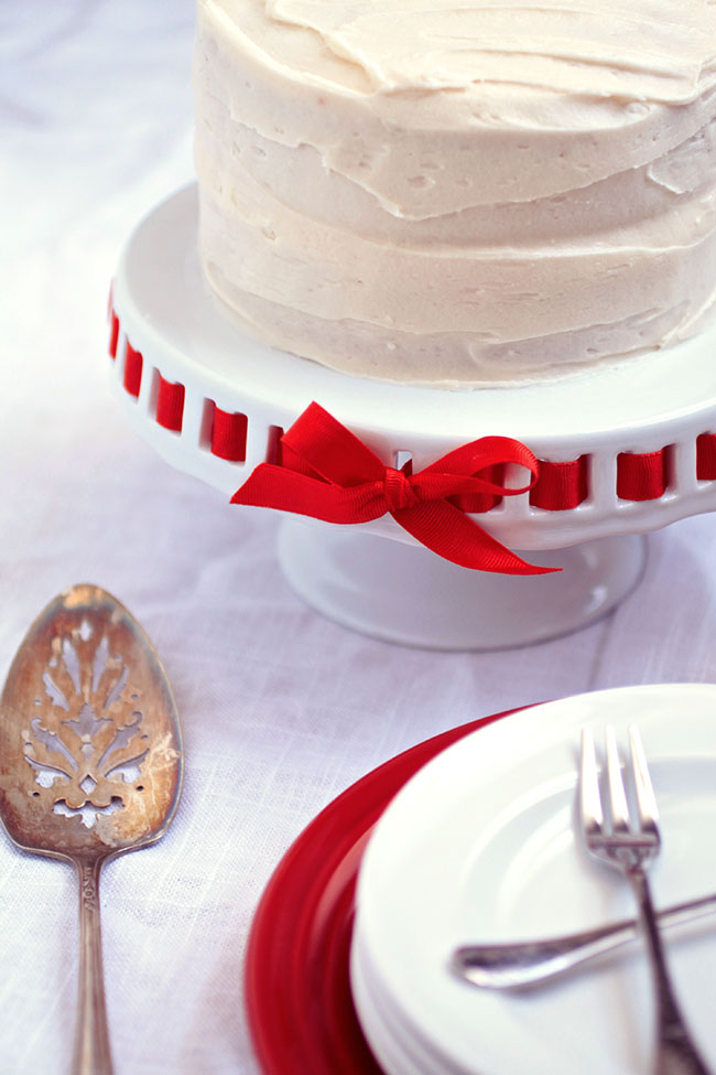 Confetti cake on a white cake stand next to a silver serving utensil.