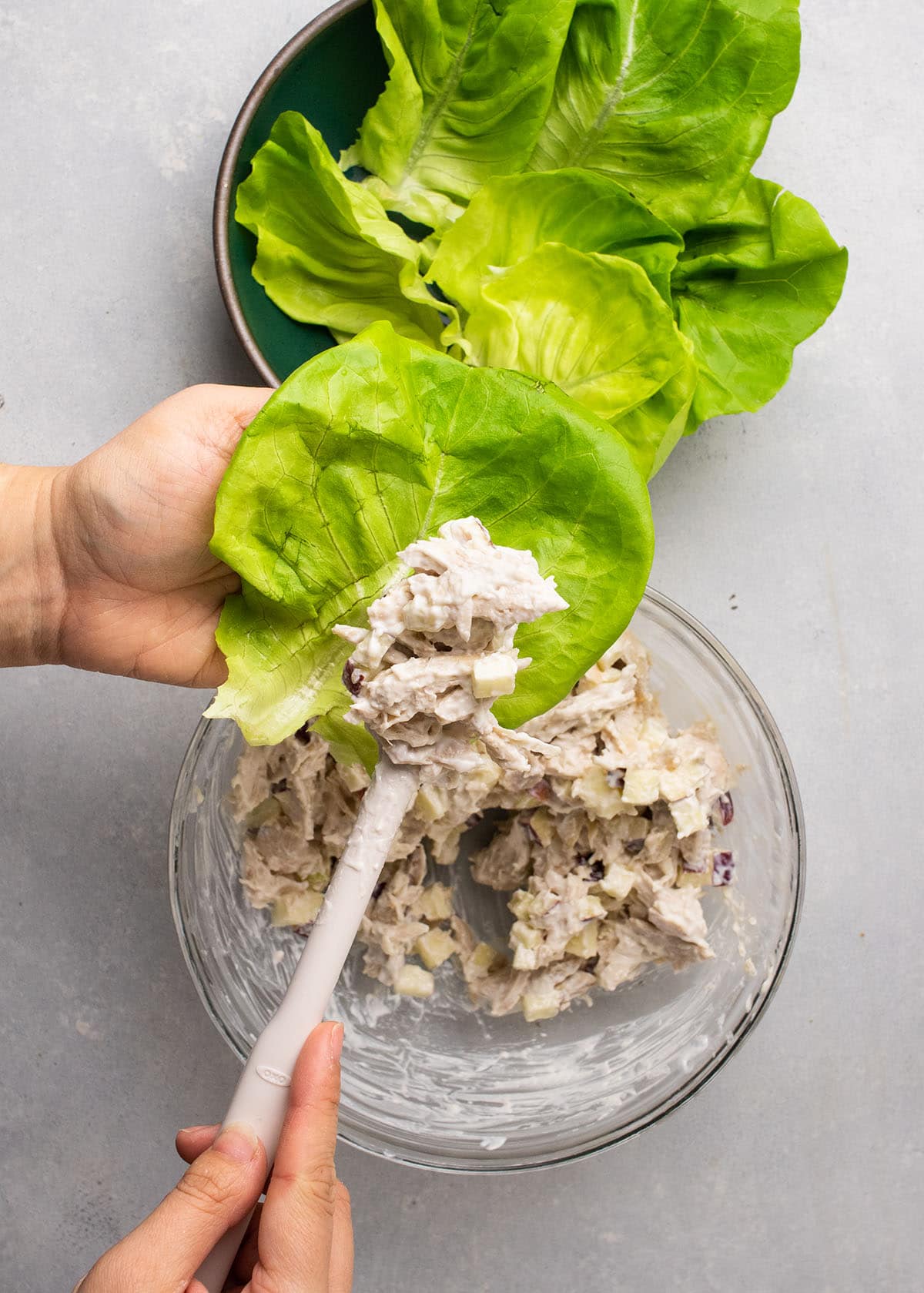 Spooning chicken salad into a large piece of lettuce.