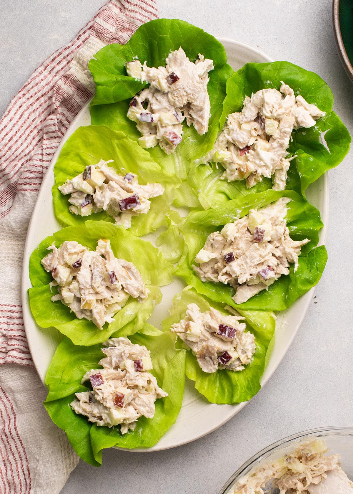 Butter lettuce leaves filled with apple chicken salad on a large white plate.