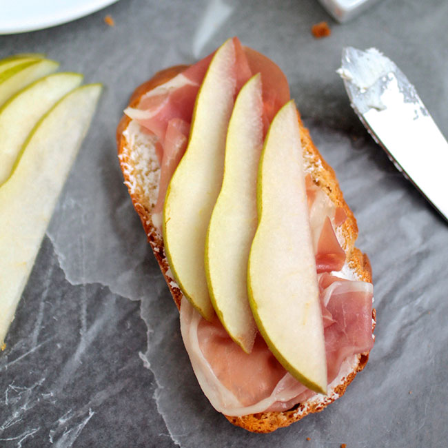 Sliced pears and prosciutto on top of a piece of crostini.