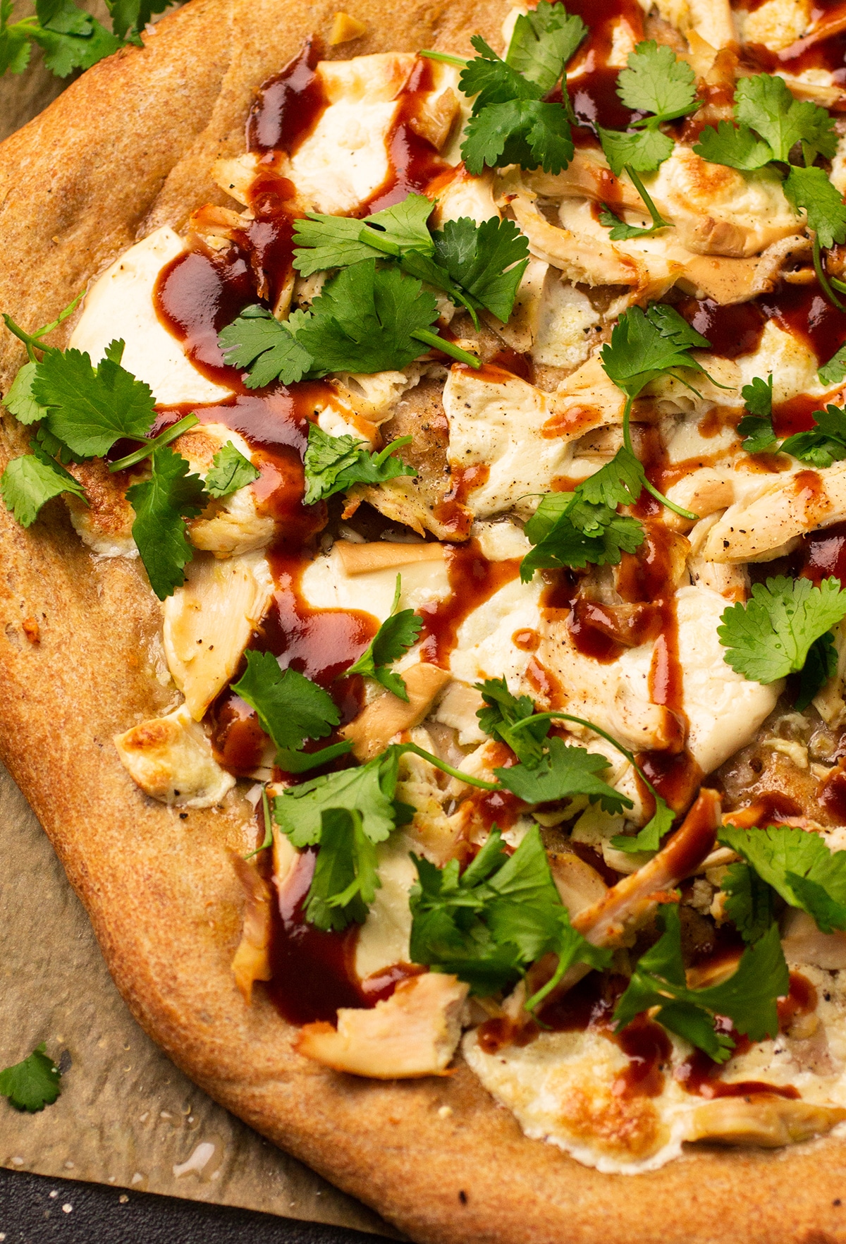Close up of pizza topped with cilantro and barbecue sauce.