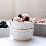 Two white bowls filled with several scoops of blackberry ice cream, topped with fresh blackberries.