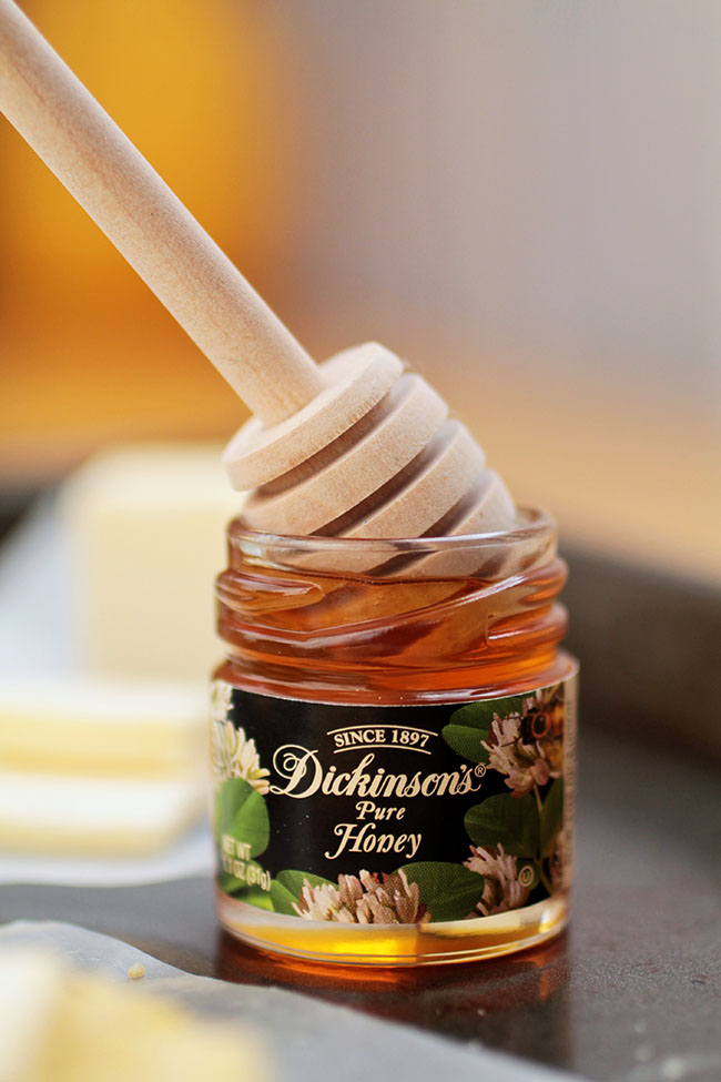 Wooden honey dipper in a small jar of honey.