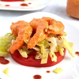 Shrimp remoulade on top of a sliced tomato and a handful of lettuce.