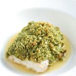 Mahi Mahi topped with pesto and breadcrumbs, sitting in a pool of butter sauce.