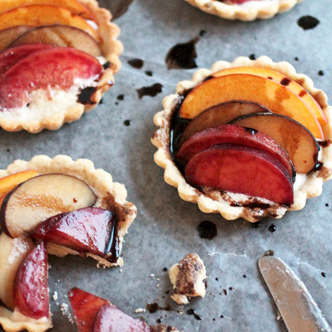 Three stone fruit tartlets topped with plum and peach slices.