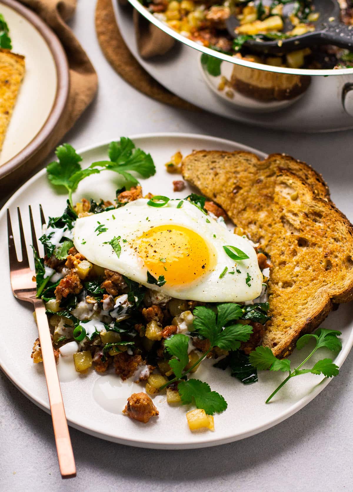 Chorizo hash on a white plate with a sunny side up egg.