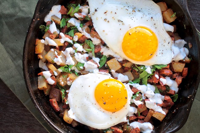 Potato hash in a cast iron skillet, topped with two over easy eggs.