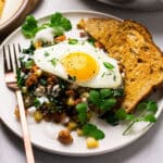 Breakfast hash with a sunny side up egg and wheat toast.