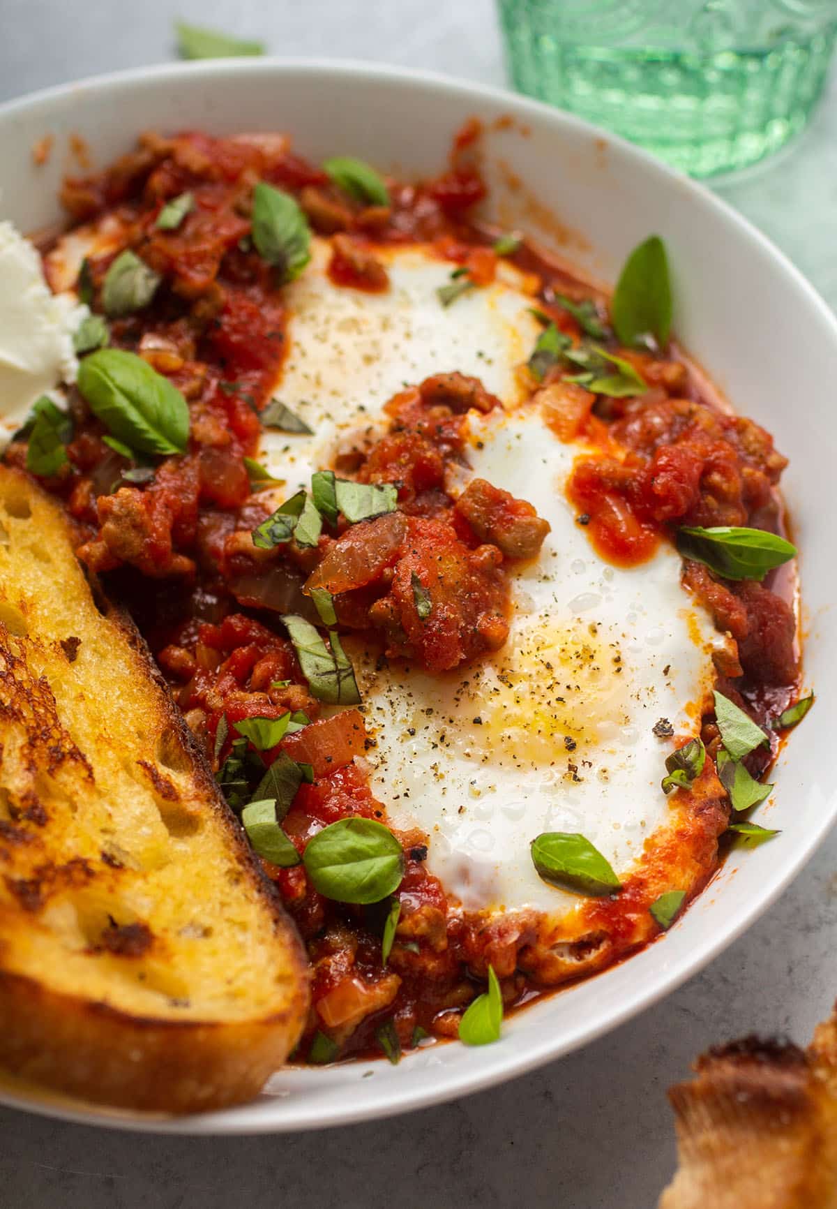 Two baked eggs with tomato sauce in a shallow white bowl.