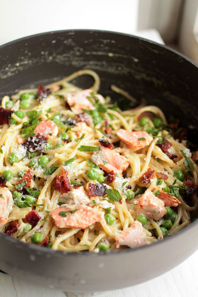 Spaghetti with salmon, peas, and bacon in a dark pot.
