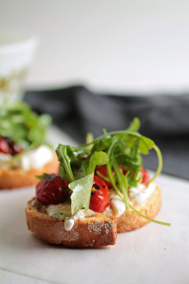 A close up of a crostini topped with fresh arugula.