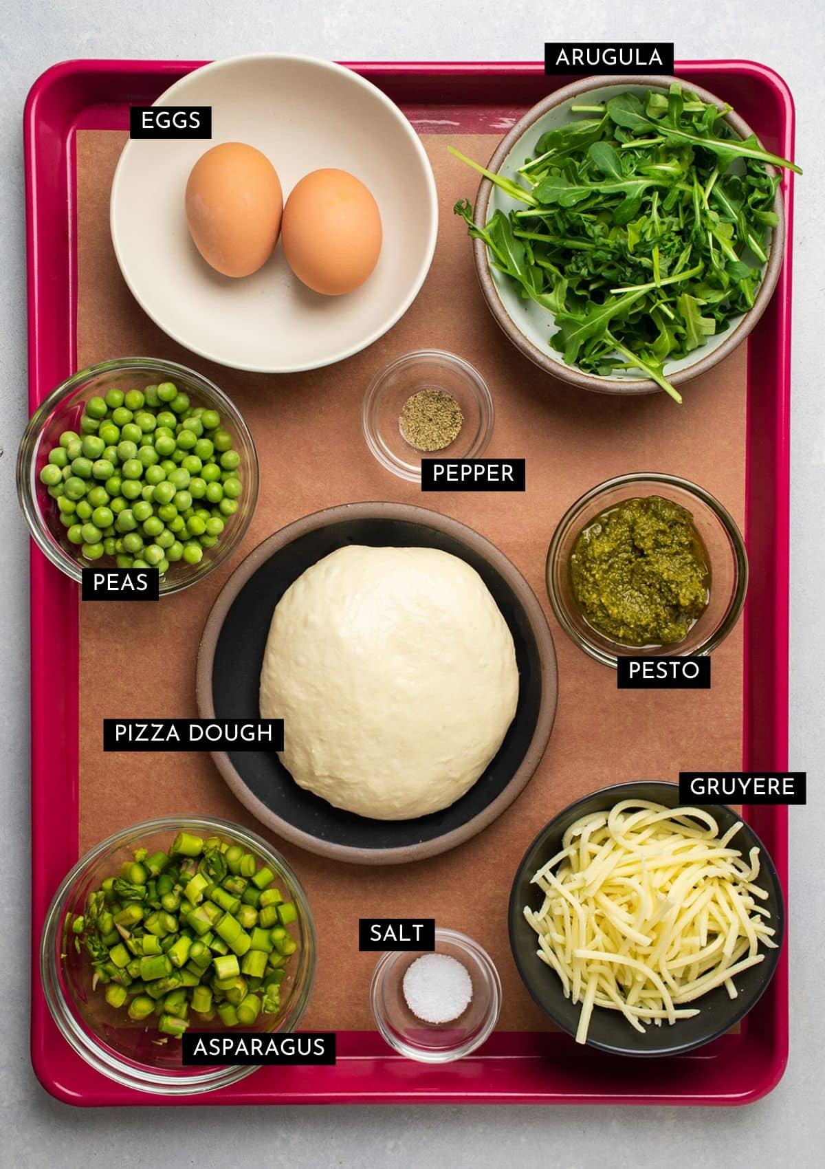 Pizza ingredients, organized into individual bowls on a pink baking sheet.