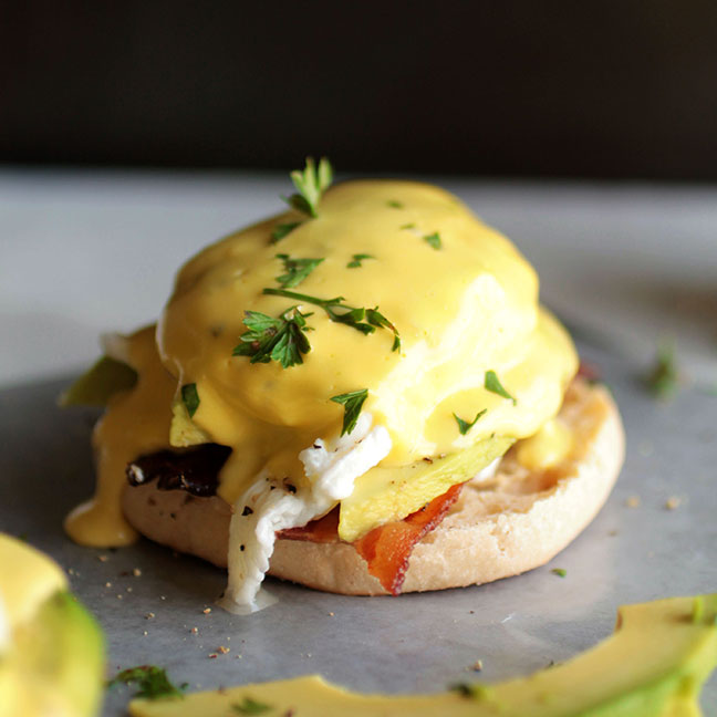 Eggs benedict topped with fresh parsley.