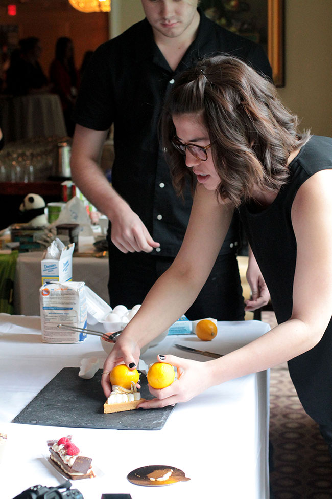 Molly Yeh arranging a slice of cake on a serving platter during a photography demonstration.
