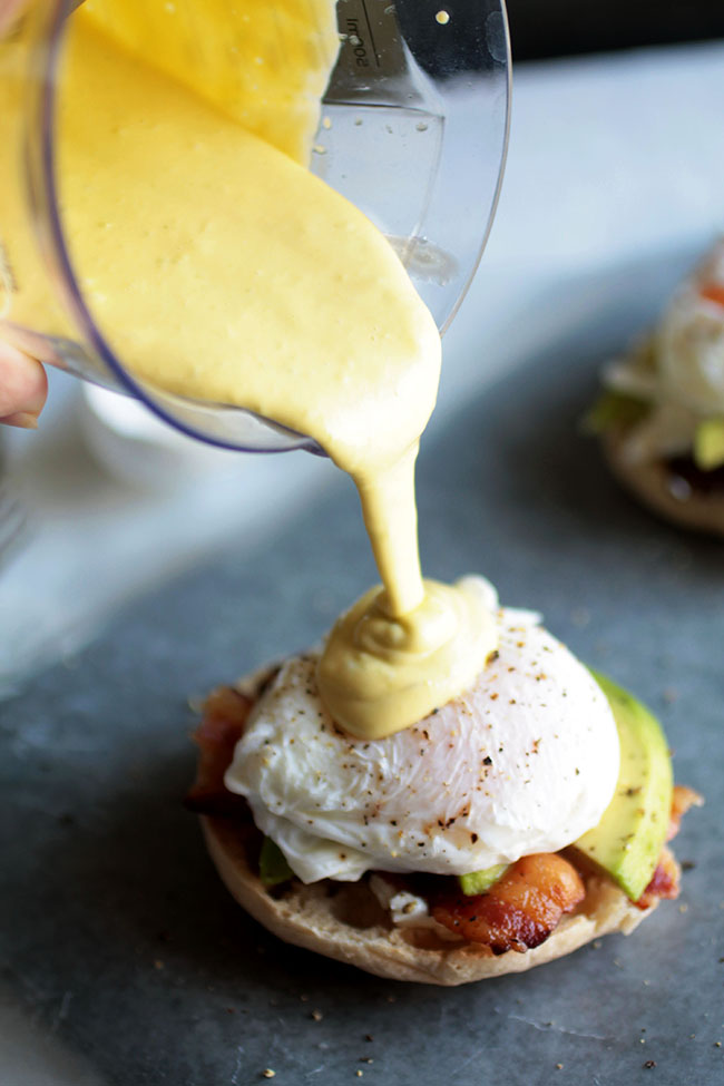 Cup pouring hollandaise sauce over a poached egg.