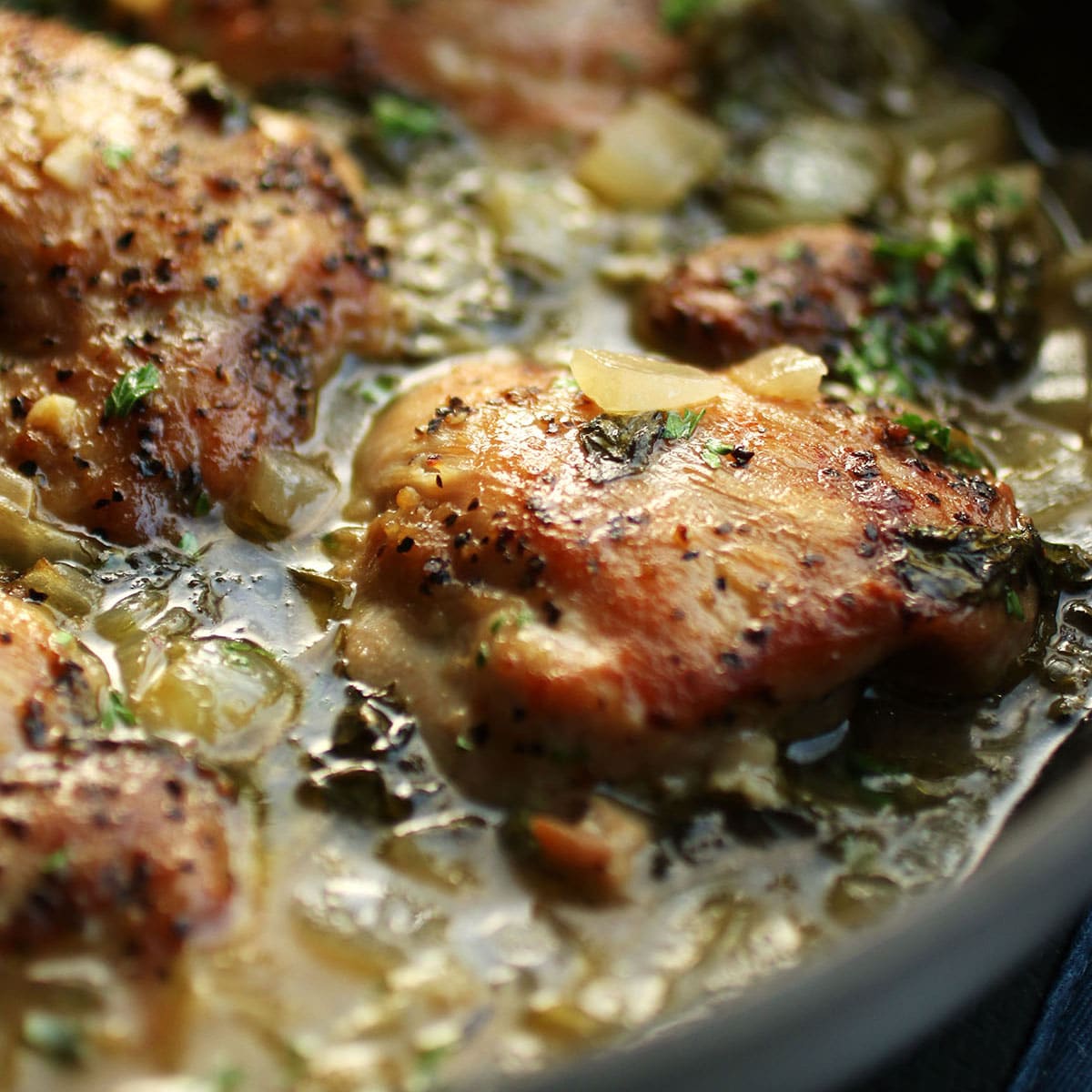 Chicken thighs in a large saucepan with lemon sauce.