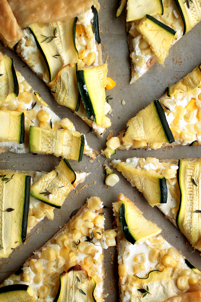 Close up of the points of several zucchini galette slices on a grey surface.