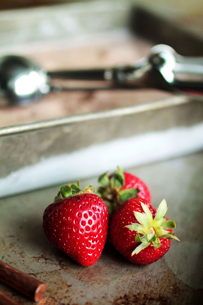 Fresh strawberries in front of a tin of strawberry ice cream.
