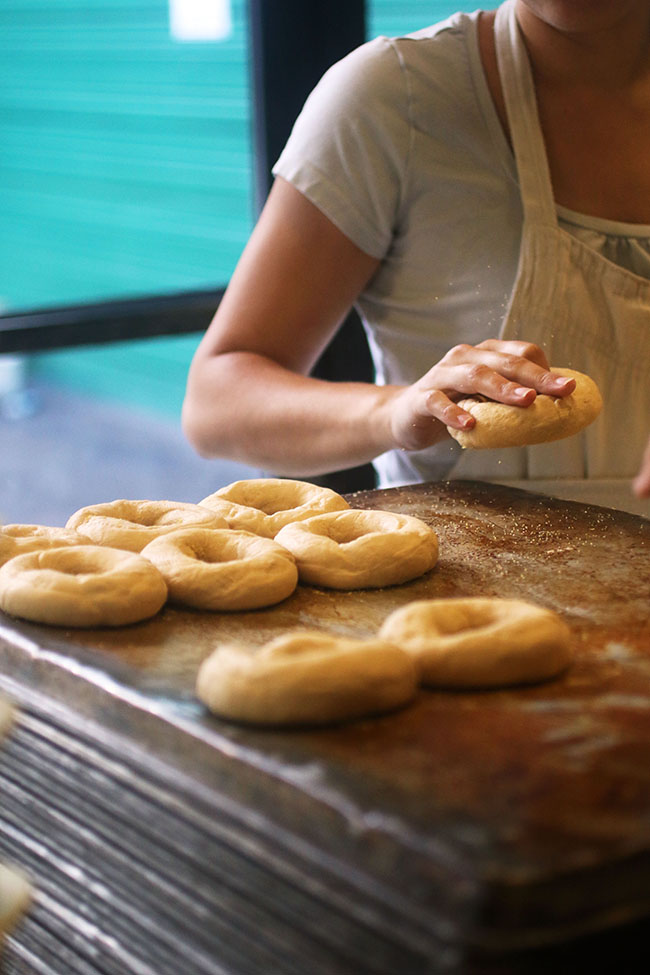 Woman forming bagels out of raw dough.