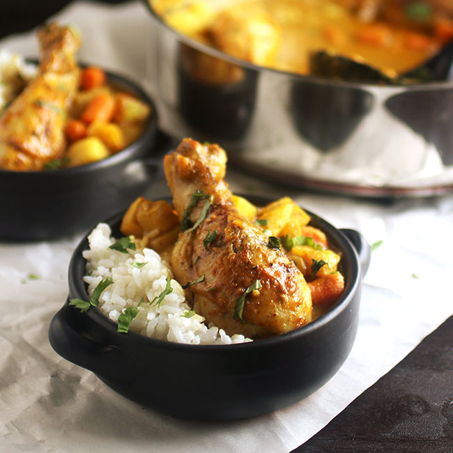 Curry chicken in a small black dish with white rice.