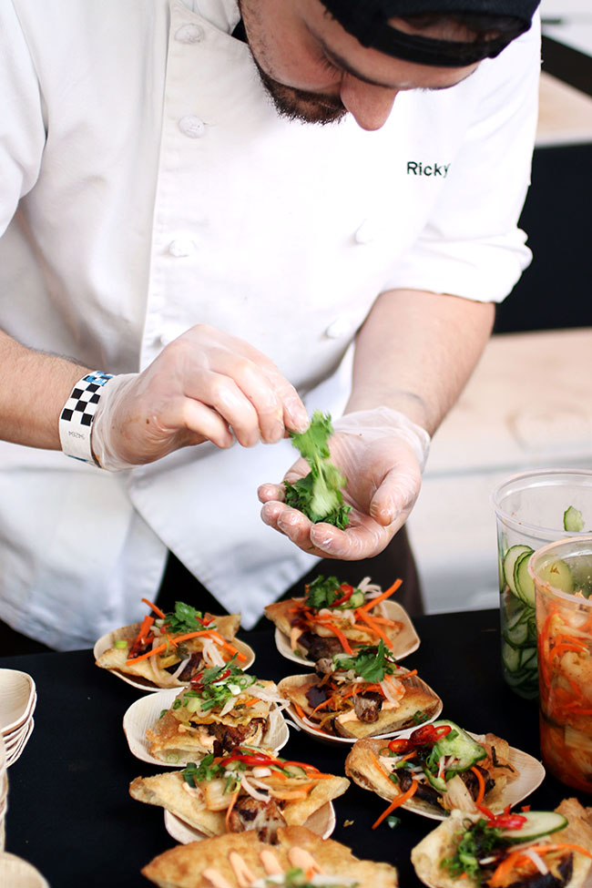 Chef adding herb garnishes to a table full of small appetizers.