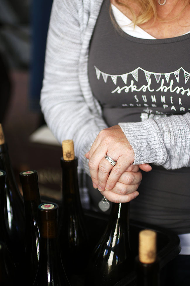 Woman's hands resting on a bottle of wine.