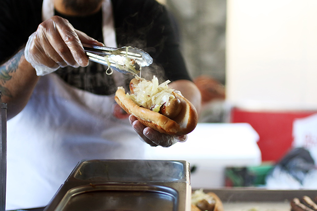 Topping a hot dog with grilled onions.