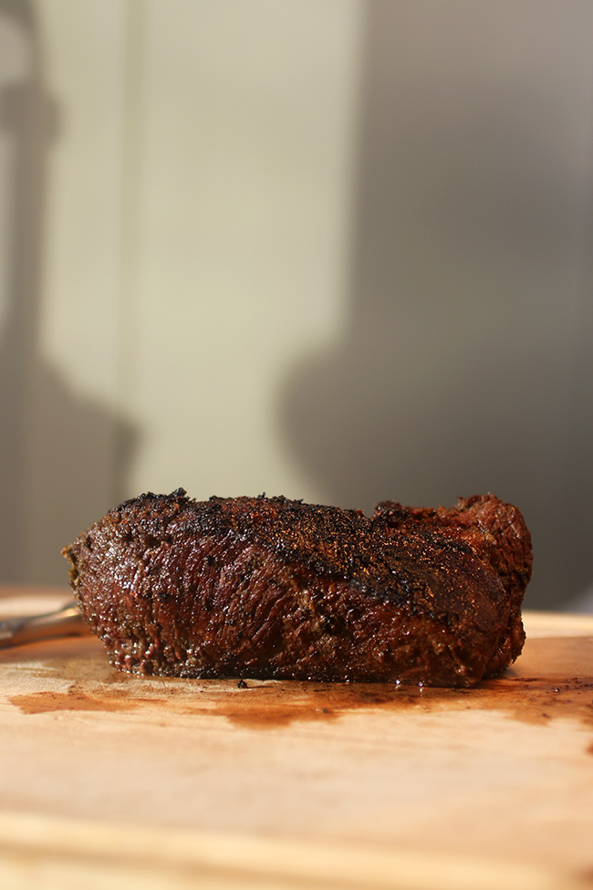 A large piece of steak on a wooden cutting board.