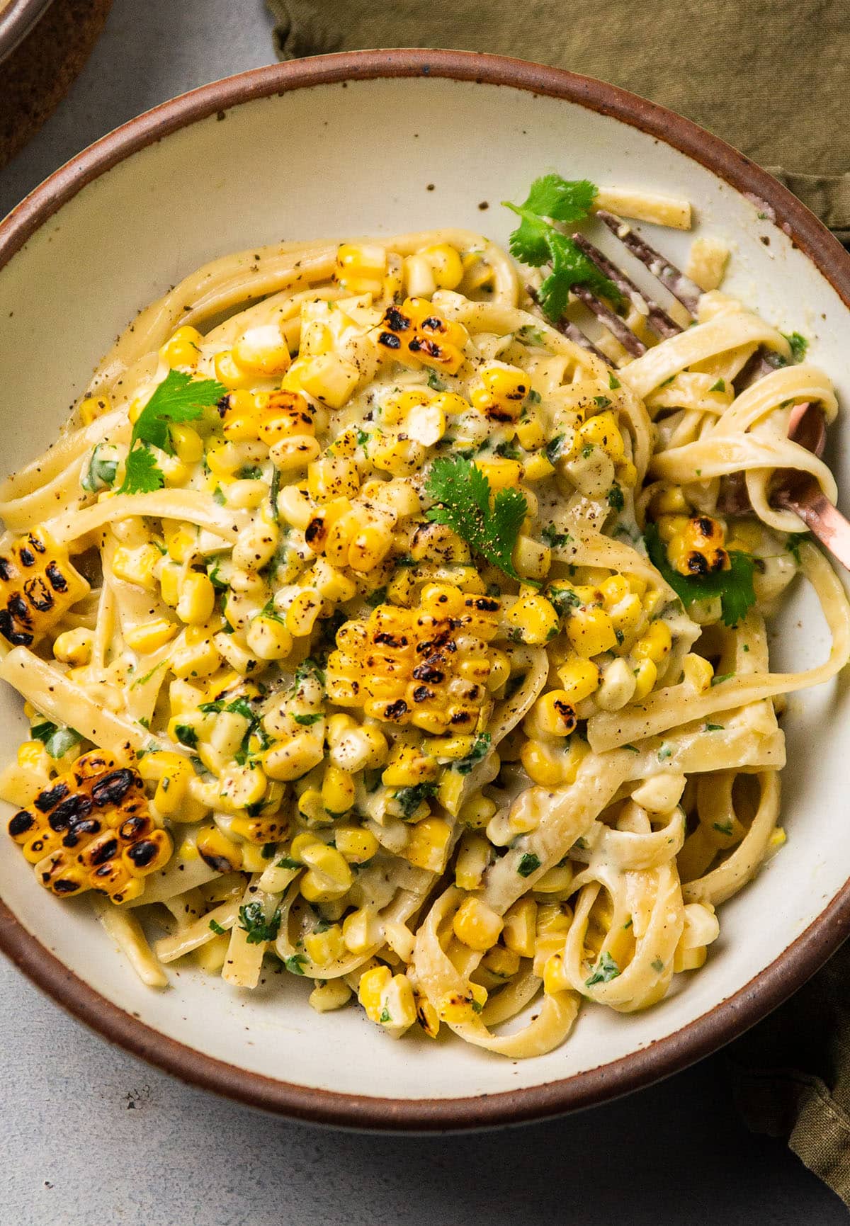 Fettuccine alfredo topped with grilled corn and fresh cilantro.