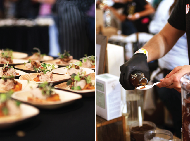 A chef pours a sauce sample into a plastic spoon next to a table of appetizers.