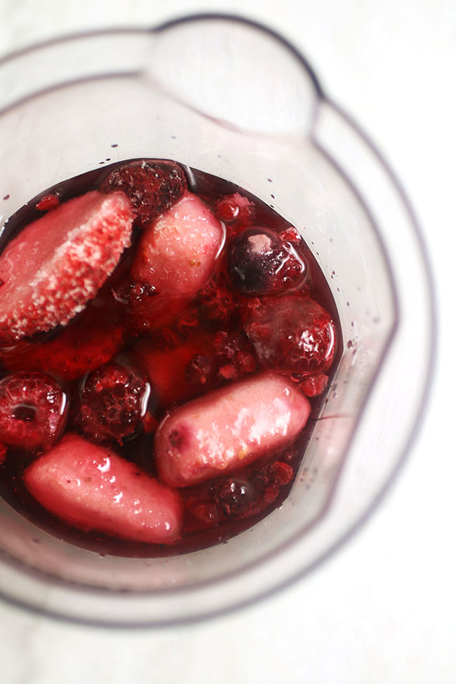 Overhead view of the beaker filled with frozen berries and cranberry juice.