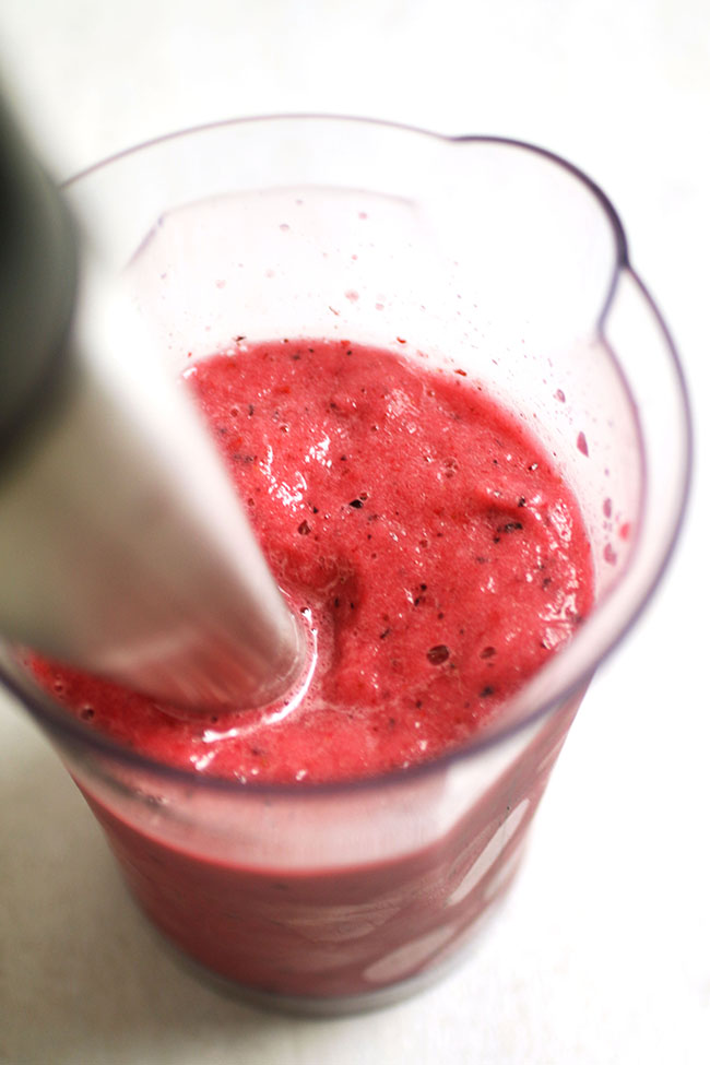 Blending a bright pink smoothie.