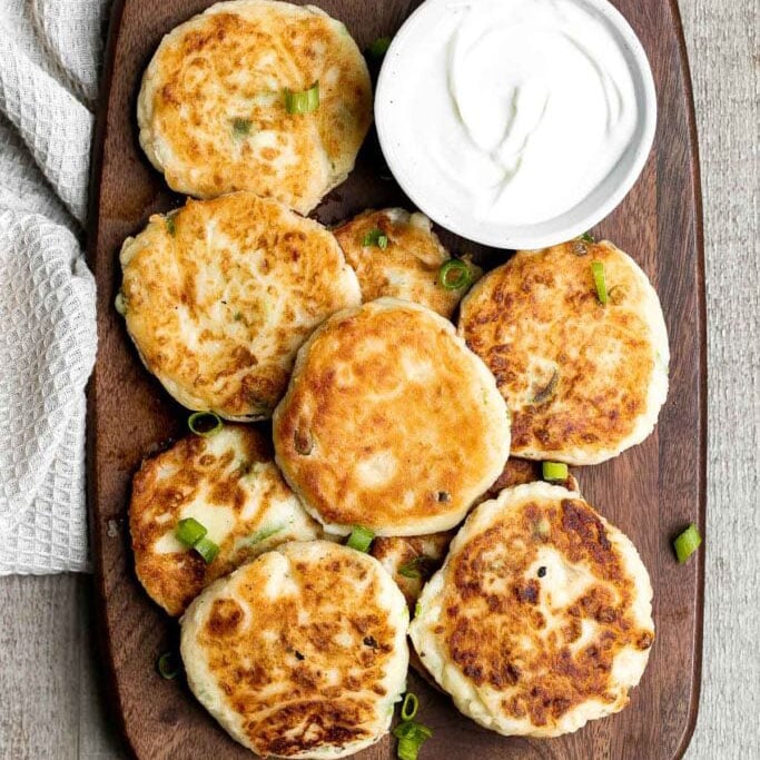 Mashed potato cakes on a wooden cutting board.