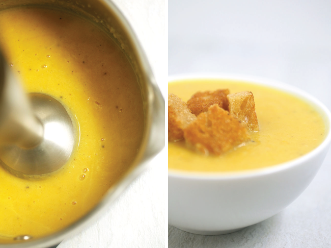 Smooth butternut squash soup in a white bowl with croutons on top.