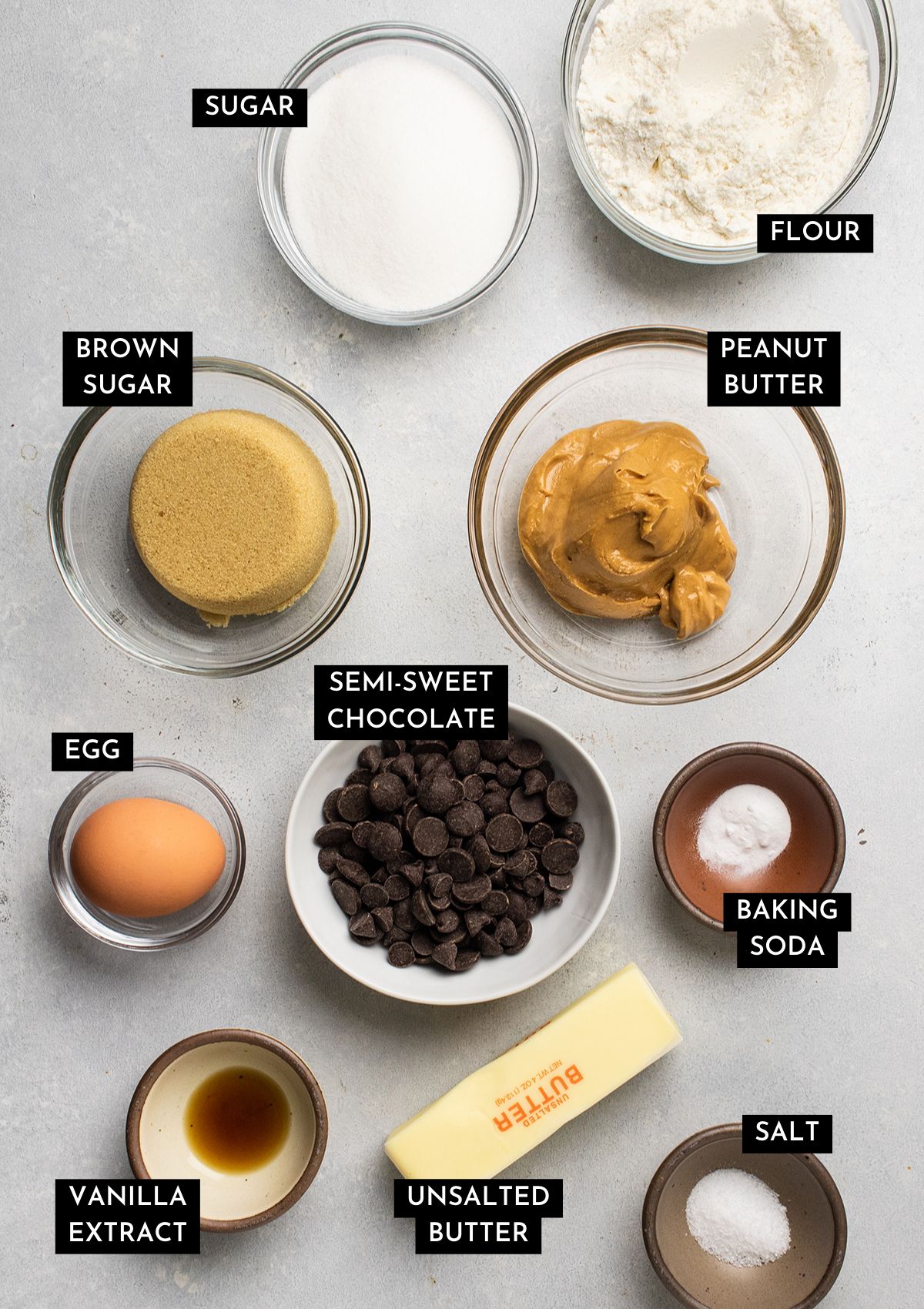 Peanut butter cookie ingredients, measured out into small bowls on a white table.