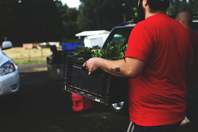 A chef carries a large box of vegetables to the car.