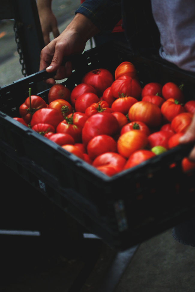 A large black box filled with fresh tomatoes.