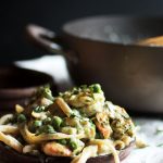 Fettuccine with peas and shrimp on a dark wooden plate.