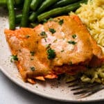 Salmon on a light brown plate with rice and green beans.
