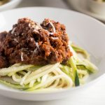 Zucchini noodles topped with bolognese sauce in a white bowl.