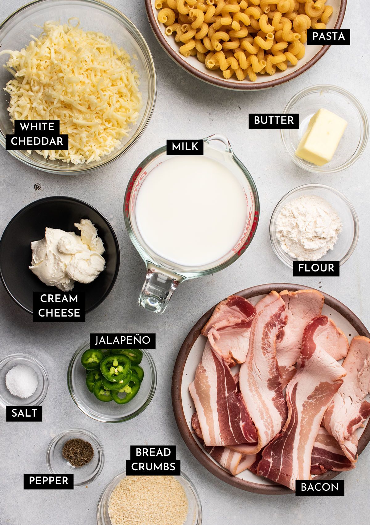 Jalapeno mac and cheese ingredients, organized into individual bowls on a white table.
