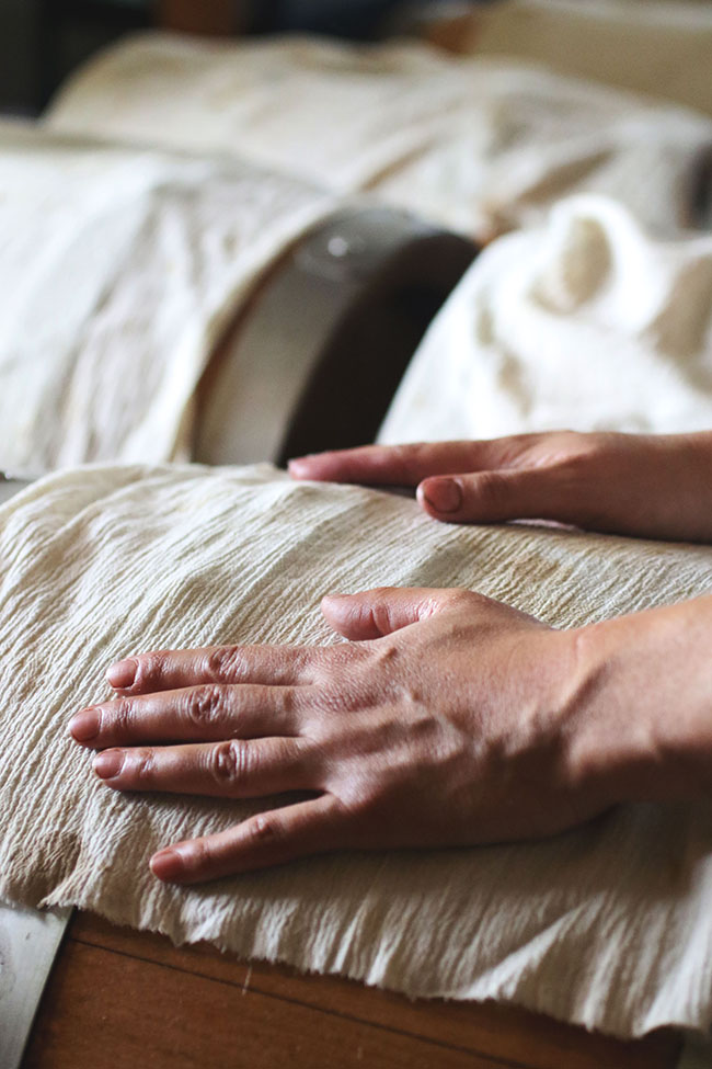 Woman's hands resting on a barrel of aging balsamic vinegar.