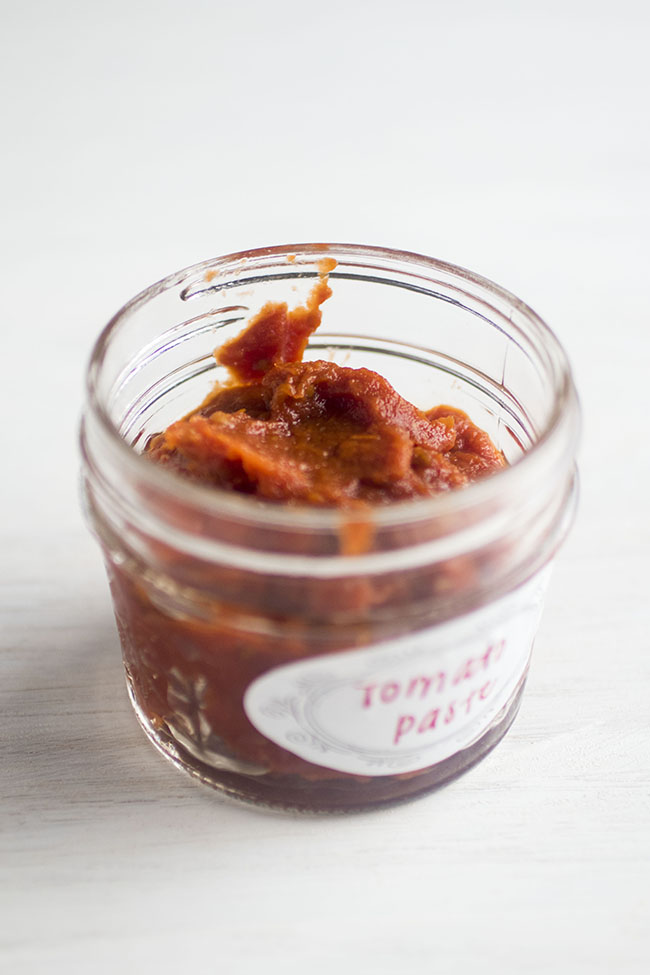 Small jar of homemade tomato paste on a white background.