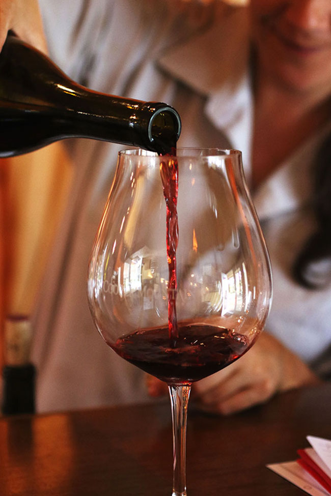 Woman pouring a glass of dark red wine.