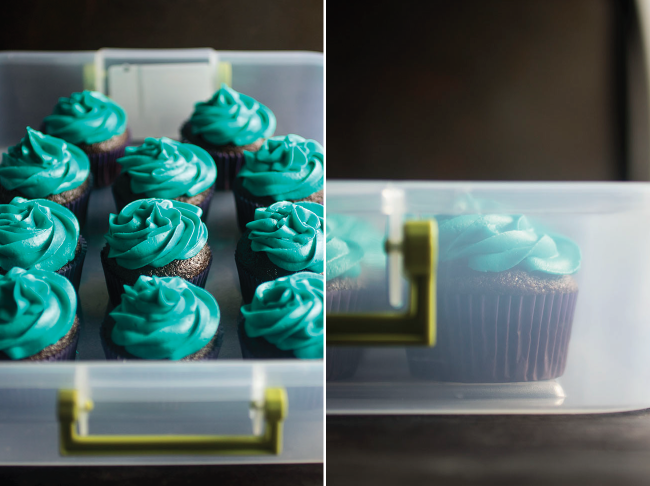 Cupcakes with blue frosting in a plastic storage bin.