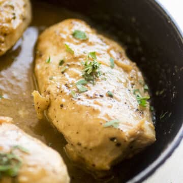 Baked chicken covered in maple dijon sauce in a cast iron skillet.