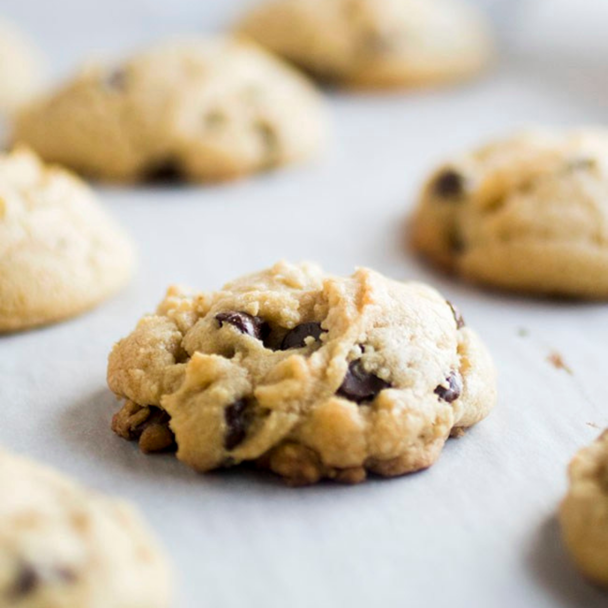 Chocolate chip cookies on a parchment paper lined baking sheet.
