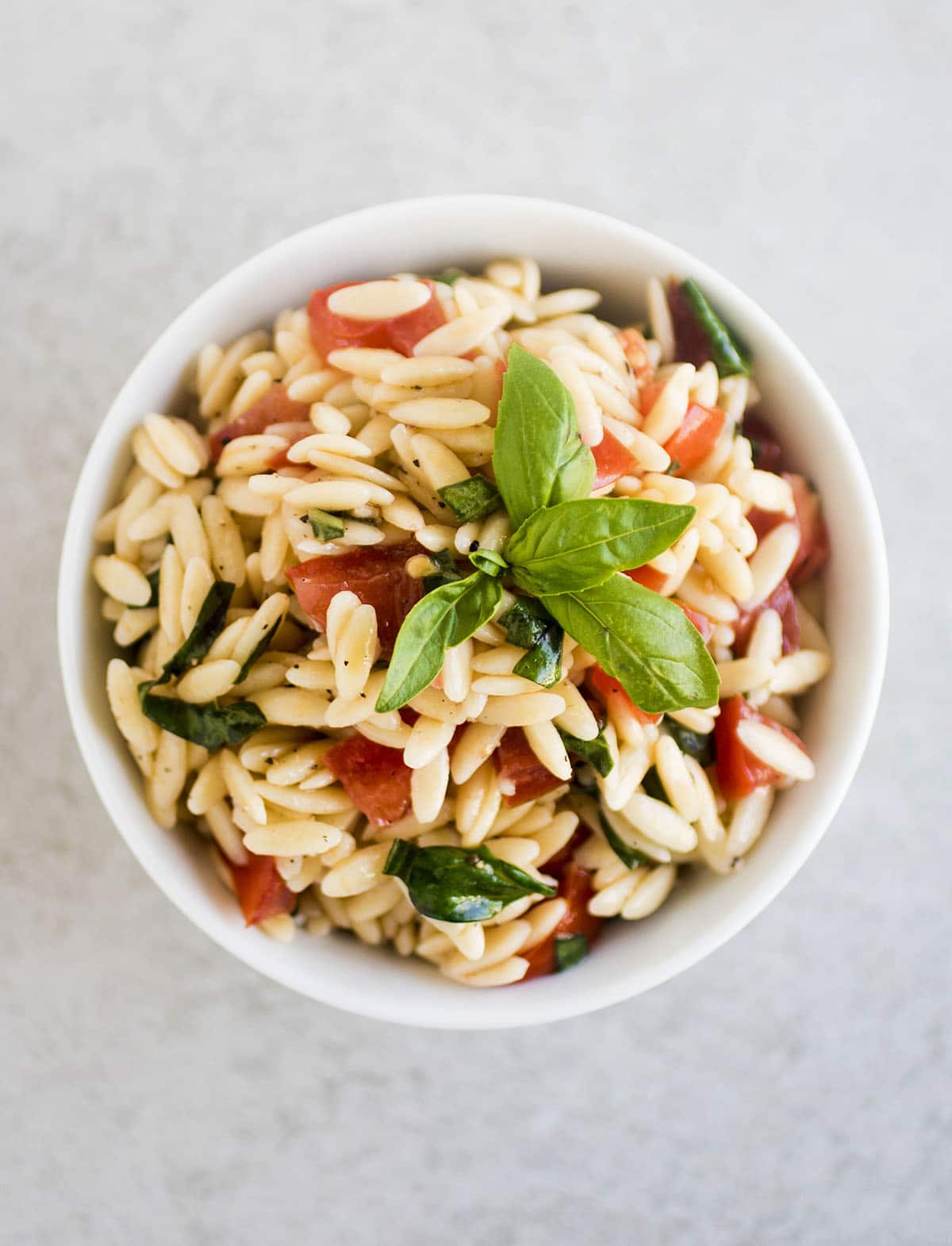 Orzo pasta salad in a shallow white bowl.