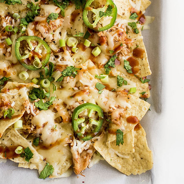 Baked nachos on a sheet pan lined with parchment paper.
